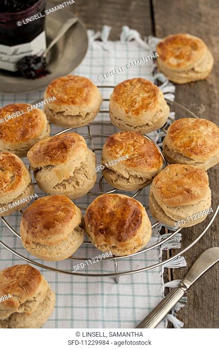Several scones on a wire rack in front of a jar of jam