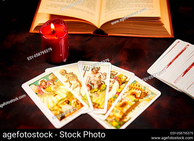Tarot cards with candlelight and book on the darkness background, Halloween and future reading concept