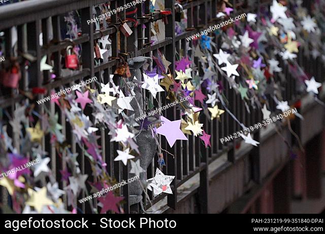 19 December 2023, Hamburg: Homemade stars made from yogurt and pudding lids hang from the Michaelis Bridge. In the world record attempt