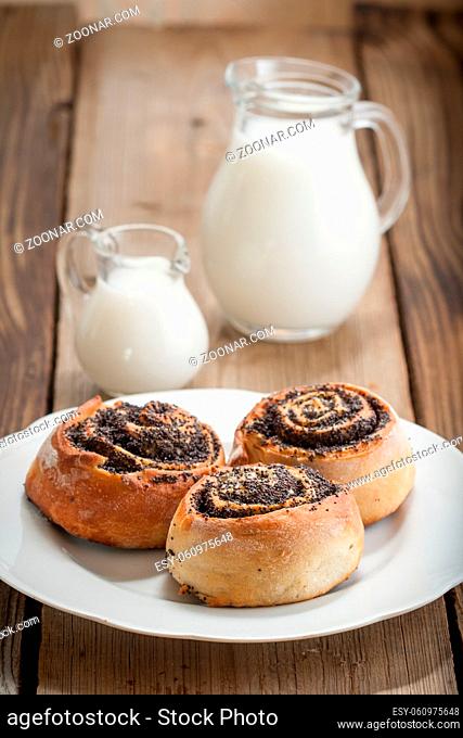 Bun with poppy seeds on a plate on a wooden background
