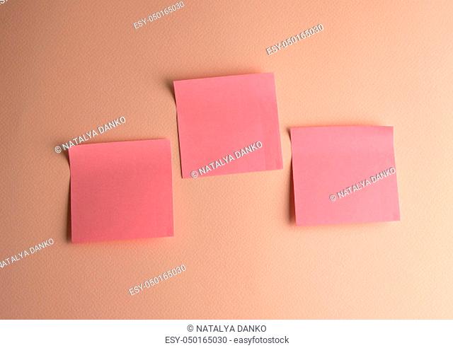 three pink paper stickers pasted on peach background, close up