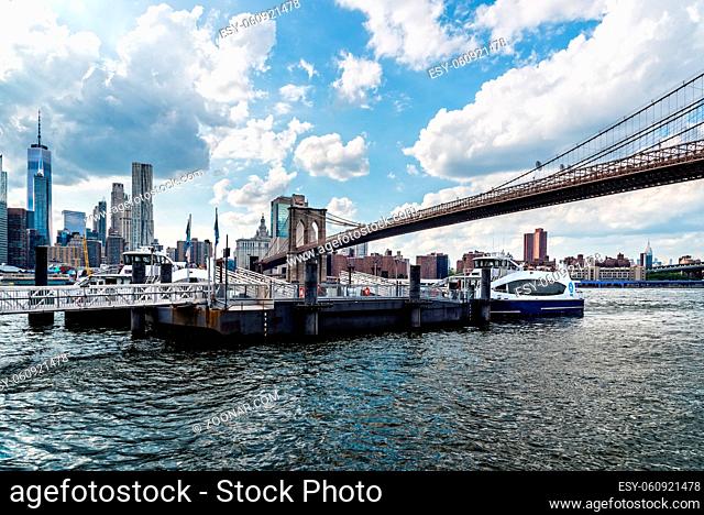 New York City, USA - June 24, 2018: Pier in East River Against Cityscape of Downtown of Manhattan and Brooklyn Bridge. Travel to New York and Transportation