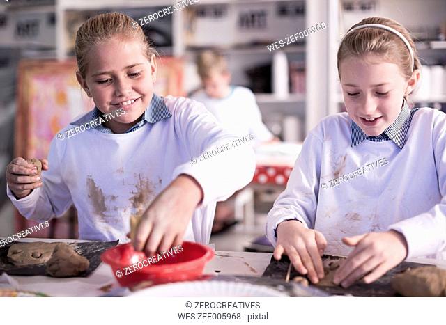 Two girls working on modeling clay in art class at school