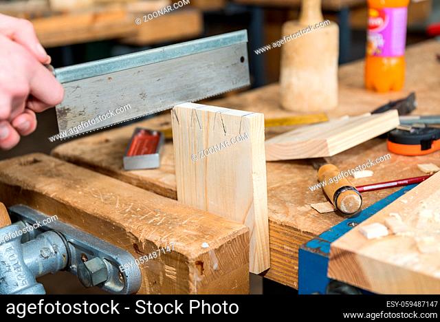 Tischler mit einer Handsäge bei Holzarbeiten in der Werkstatt - Nahaufnahme Holzsäge