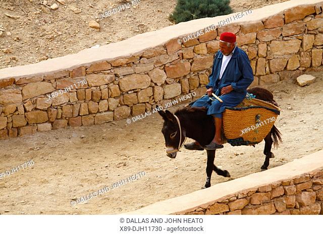 Africa, Tunisia, Berber Village of Chenini, Troglodyte Cave dwellings, Local Berber riding Donkey