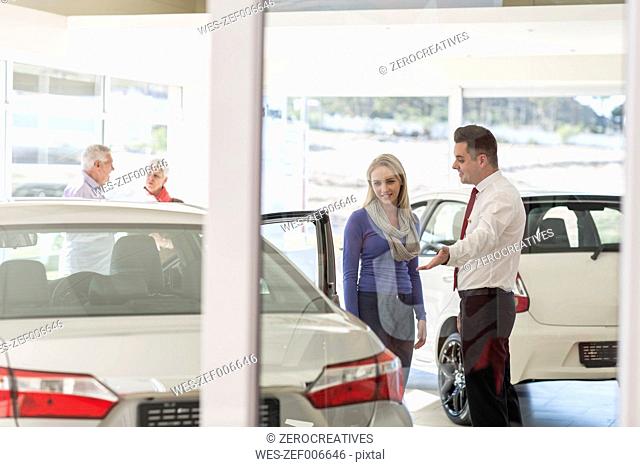 Car dealer talking to woman in showroom