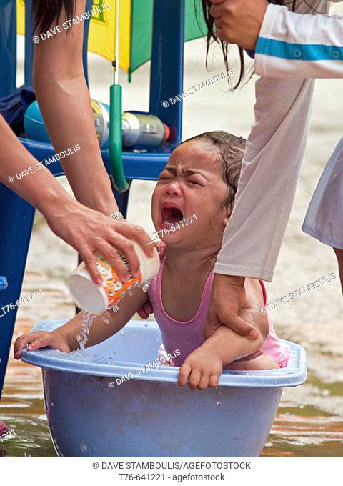 Baby cries while getting a curbside bath during the Lao Songkran New Year, Luang Prabang
