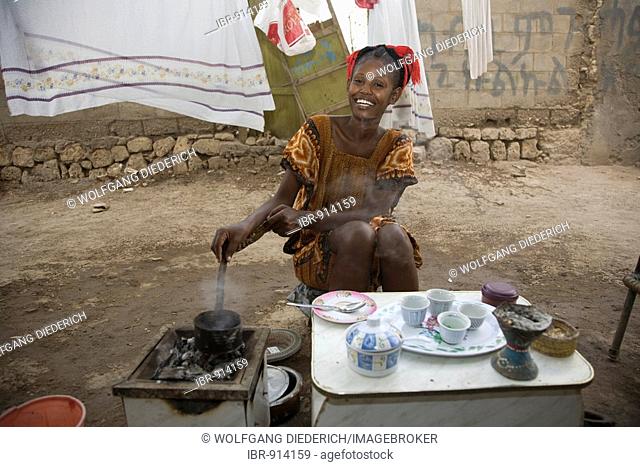 Young woman, 20-25 years old, performing a coffee ceremony in the open air with freshly roasted coffee beans with high-summer temperatures of 45°C, Red Sea