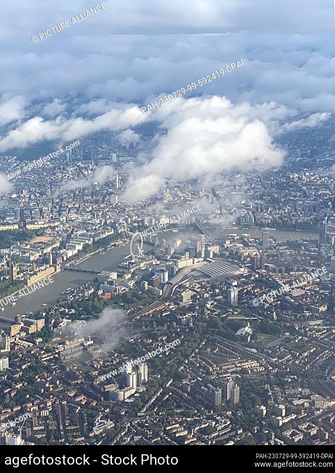 29 July 2023, Great Britain, London: View from the airplane of the city with the London Eye Ferris wheel (M) and the British Parliament (l)