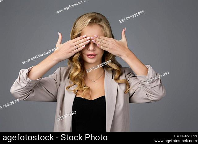 Portrait of beautiful woman closes her eyes with hand on gray background. I can not see