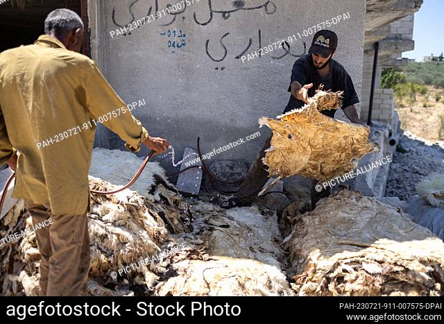 20 July 2023, Syria, Azmarin: Syrian workers prepare cattle hides for tanning and natural leather production at a workshop in the Syrian village of Azmarin