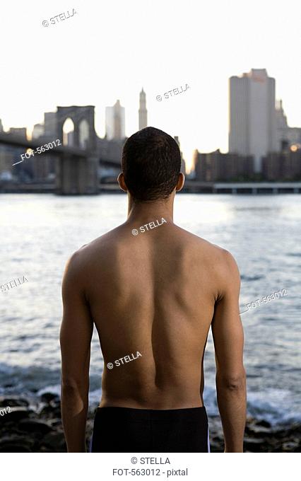 A semi dressed man looking across river to Manhattan