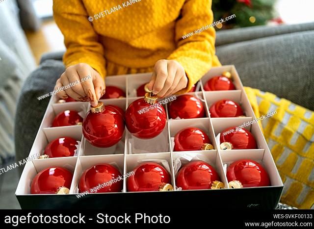 Girl with box of Christmas ornaments at home