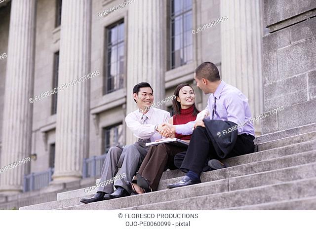 Three businesspeople outdoors on staircase