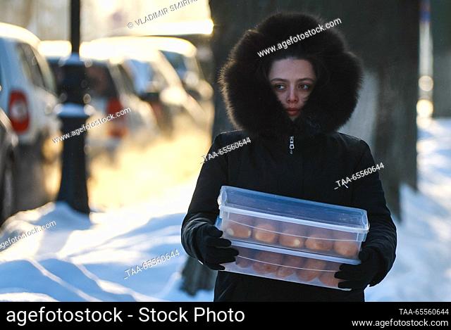 RUSSIA, VLADIMIR REGION - DECEMBER 8, 2023: A woman carries boxes with pirozhki [baked stuffed buns] in the town of Suzdal