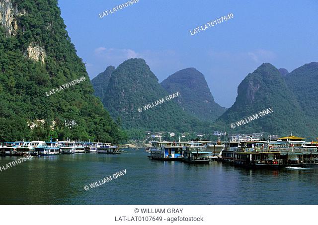 Yangshuo. Tourist, passenger boats on river. Wooded slopes of limestone peaks, pinnacles