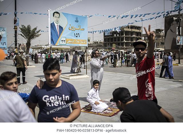 dpatop - An Iraqi man and his son attend Friday prayers backdropped by campaign posters for the upcoming parliamentary elections in the Sadr City suburb of...