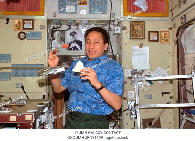 Astronaut Edward T. Lu, Expedition 7 NASA ISS science officer and flight engineer, eats a meal in the Zvezda Service Module on the International Space Station...