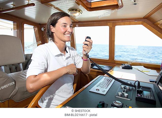 Caucasian woman steering boat and using radio