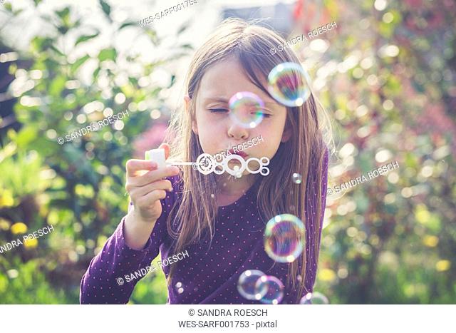 Girl blowing soap bubbles in a garden
