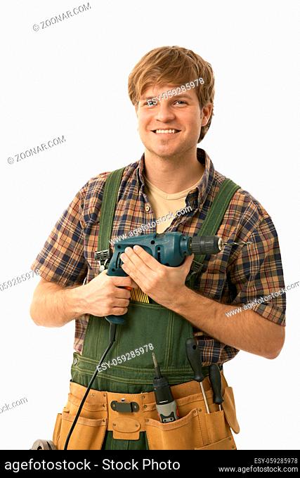 Young handyman holding power drill, smiling. Isolated on white