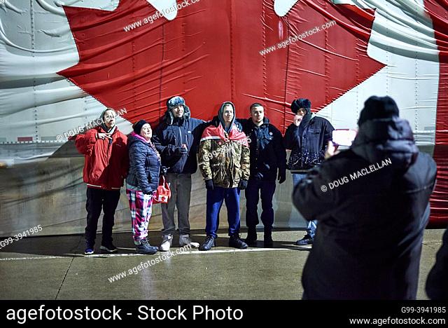 A group of six people pose in front of a large Canadian flag on the side of a semi-trailer truck on 11 February 2022 in Windsor
