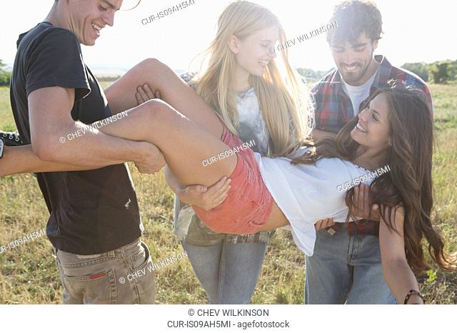 Three friends lifting young woman