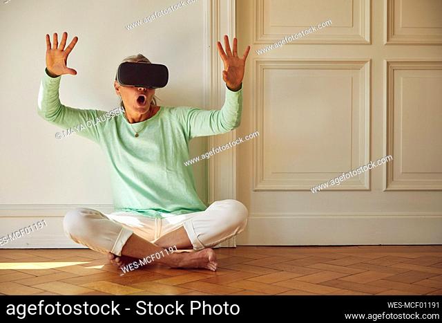 Woman using VR glasses while sitting on floor at home