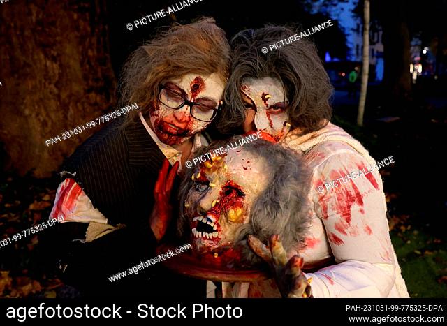 31 October 2023, North Rhine-Westphalia, Essen: Anke Kulik (l) and Anna Sommerstange as zombies with severed heads at Zombie Day in Essen