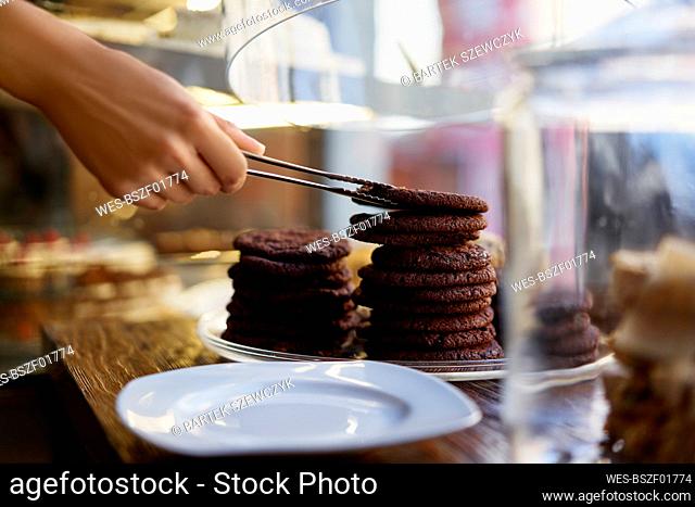 Hand of barista removing cookie biscuits while working at cafe