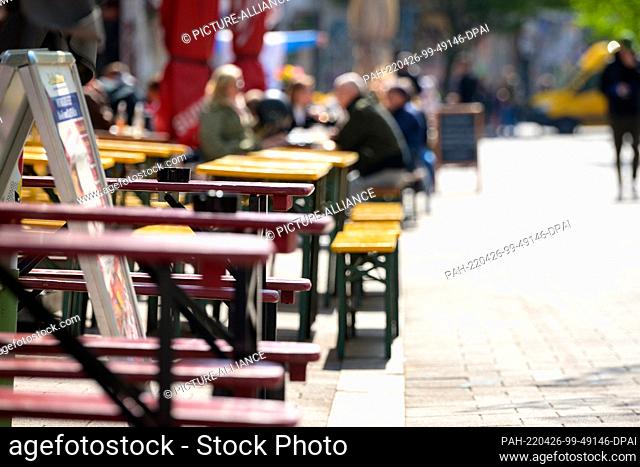 26 April 2022, Hamburg: Restaurant guests sit in the sun at tables outside bars in the Schanzenviertel. The red-green Hamburg Senate will discuss on Tuesday how...