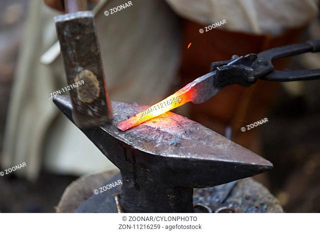 Blacksmith hammering hot metal arrow