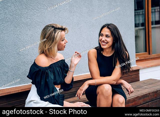 Female friends talking to each other sitting on bench