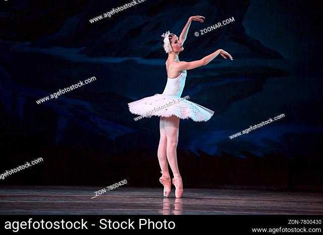 Prima ballerina white swan on the stage gracefully dancing on decorative theatrical background. Ballet Swan Lake, the Opera House in Kiev, Ukraine