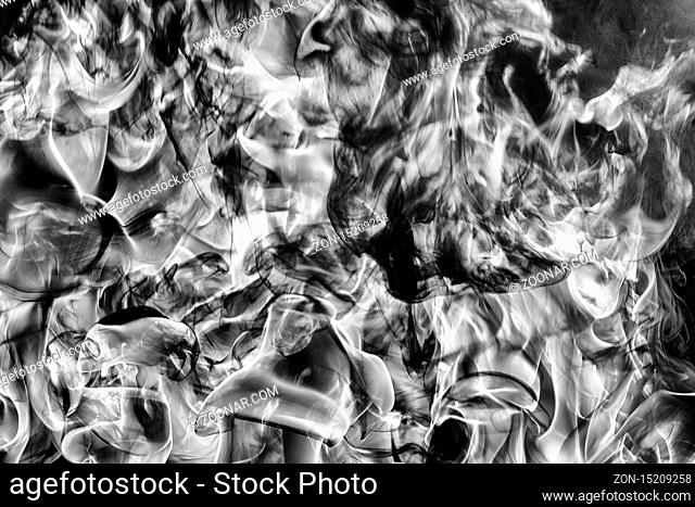 Abstract clouds of natural black smoke and white huge flame of strong fire. Dangerous firestorm abstract background. Monochrome photography