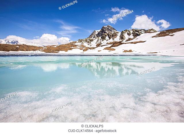 Reflections of spring on Lake Emet in thaw, Madesimo, Chiavenna Valley, Spluga Valley, Valtellina, Lombardy, Italy, Europe