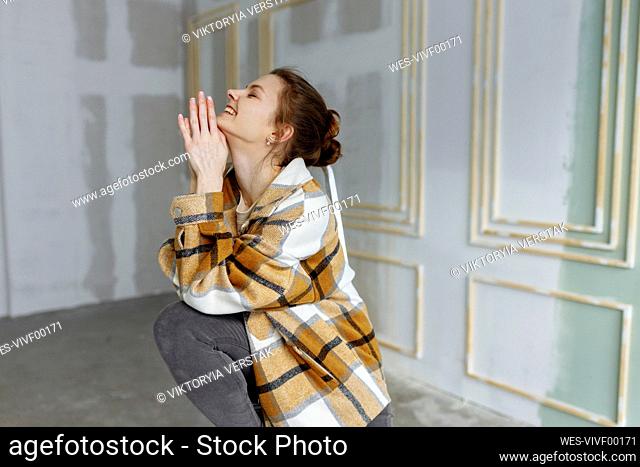 Happy woman with eyes closed and hands clasped at home