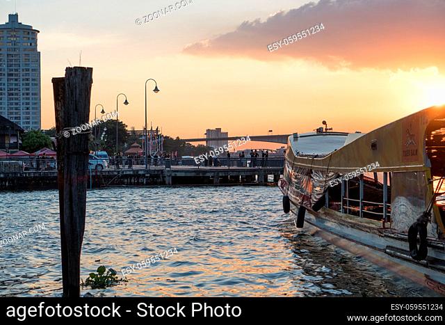 Pier for traveling along Chao Phraya River on regular city boat line in Bangkok during beautiful sunset, Thailand