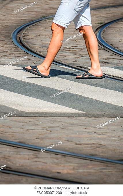 Man in flip flops crossing the road in town in summer