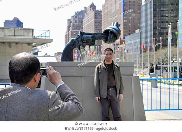 tourists taking souvenir photos in front of the knotted gun, non-violence sculpture from Reuterswaerd in front of UN Headquarter, USA, USA, New York City