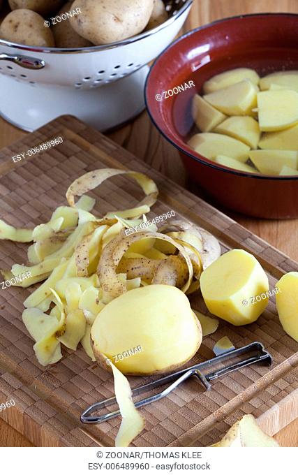 Cutting board with potatoes and potato peeler