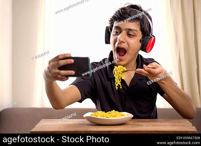 A CHEERFUL TEENAGER CLICKING SELFIE WHILE EATING MAGGI