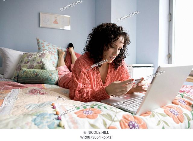 woman lying on a bed with a notebook computer