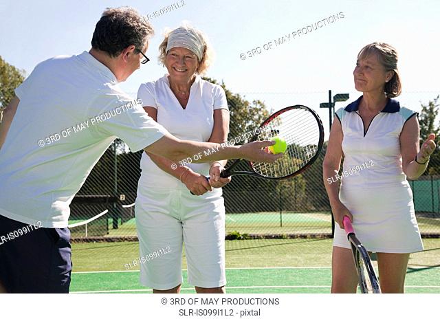 Senior and mature adults practising on tennis courts