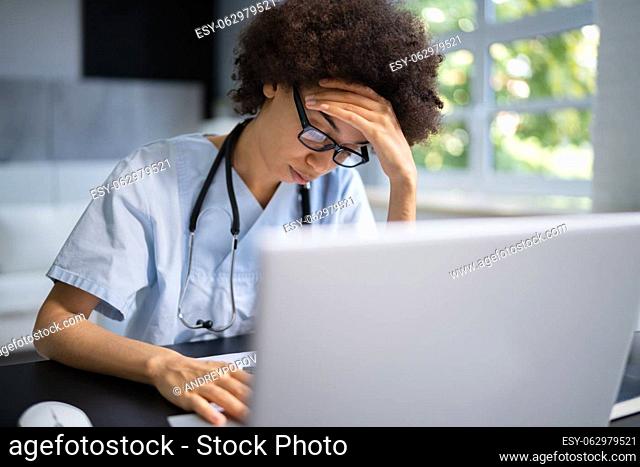 Frustrated Overworked Doctor In Hospital Looking At Computer