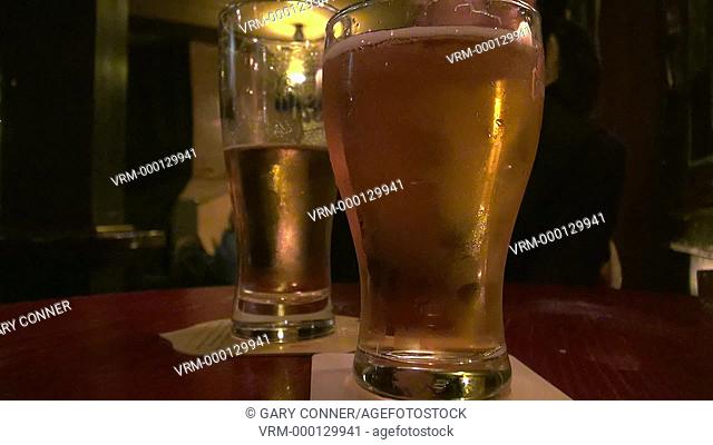 Two beers served in a pub, woman drinks beer and puts it down, in Tokyo, Japan