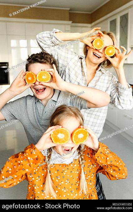 Playful family covering eyes with slices of oranges at home