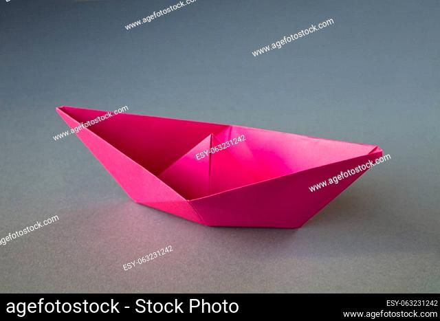 Pink paper boat origami isolated on a blank grey background