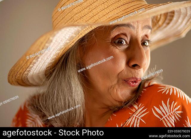 A Happy old woman expressing wonder wearing a hat