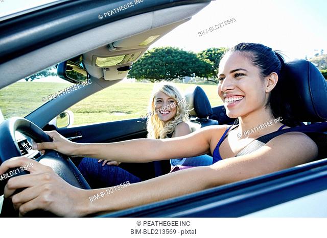 Excited women driving convertible on road trip